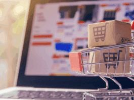 Miniature shopping cart holding laptop representing electronics prices rising
