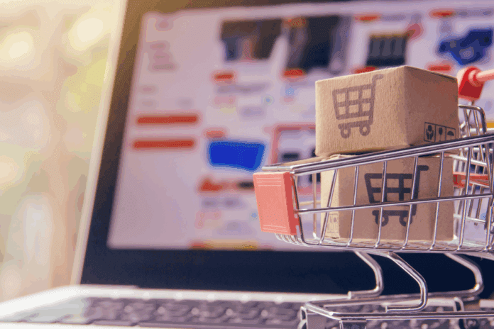 Miniature shopping cart holding laptop representing electronics prices rising